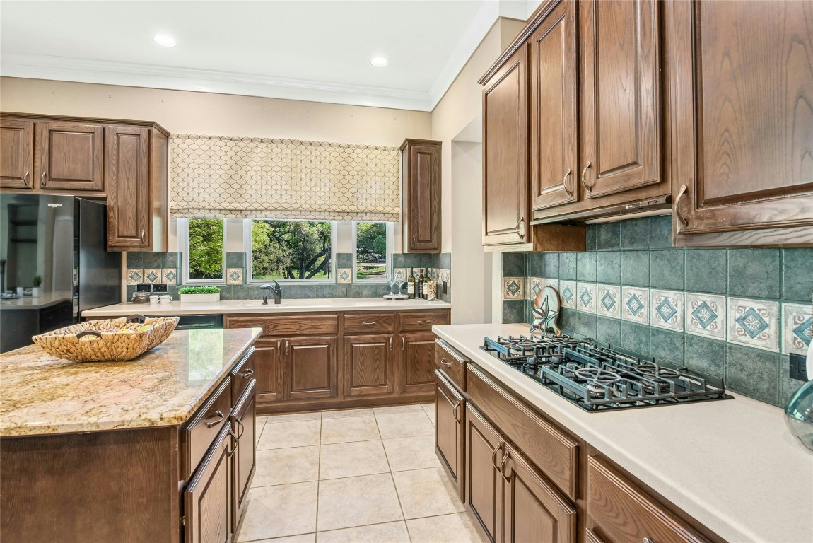 316 Trail Of The Flowers Georgetown, TX 78633 - Photo 10 of 40 a kitchen with granite countertop a sink a stove and a wooden cabinets