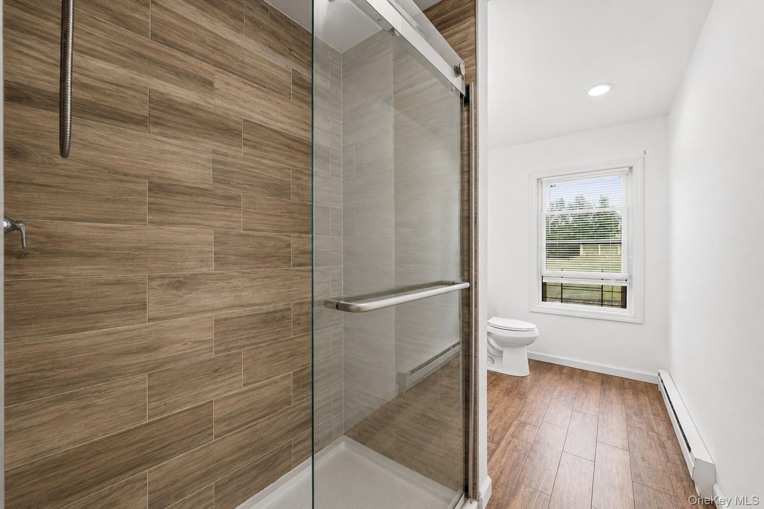 931 Diven Street Peekskill, NY 10566 - Photo 19 of 29 Second floor unit walk-in shower with clear glass enclosure and wood-finish tile surround