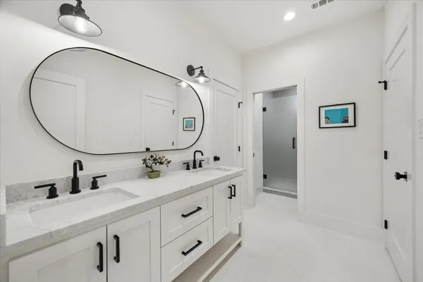 a bathroom with a double vanity sink mirror and shower