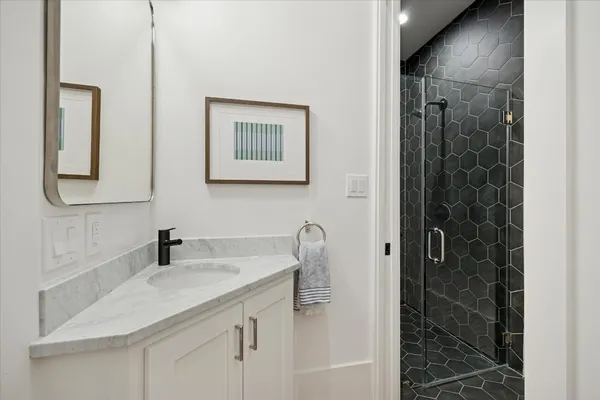 a bathroom with a granite countertop sink a mirror and shower
