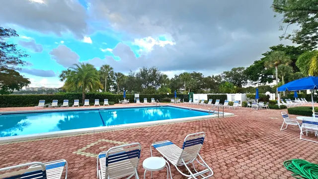 a view of a swimming pool with lawn chairs under an umbrella