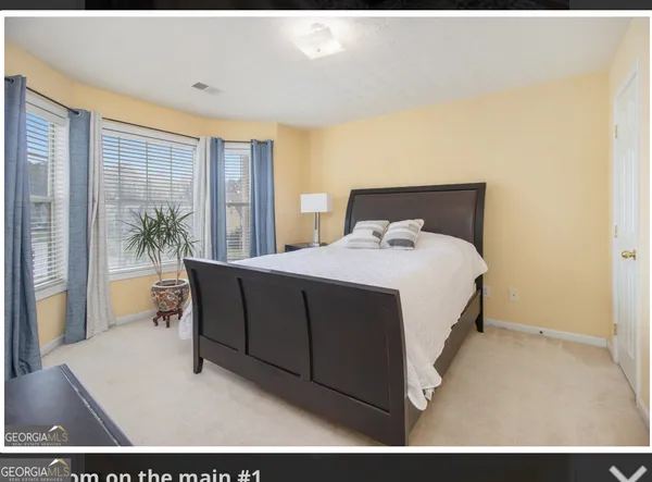 a bedroom with a bed and large windows