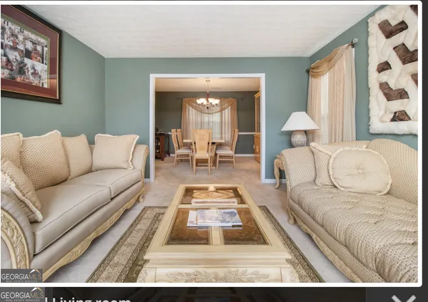 a living room with furniture and a large mirror next to a window