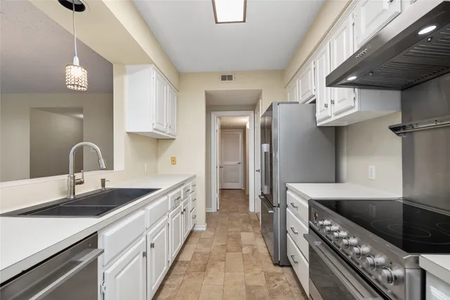 a kitchen with stainless steel appliances granite countertop a sink a stove and a refrigerator