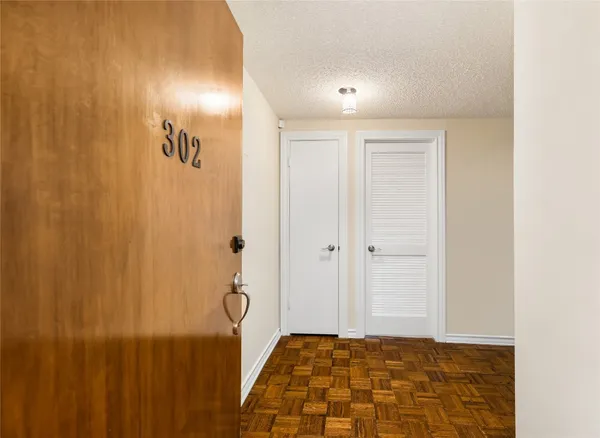 a view of a hallway with wooden floor and a bathroom