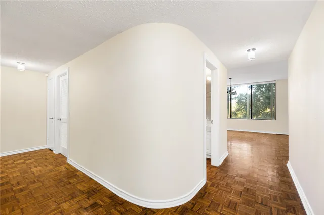 a view of a hallway with wooden floor and a bathroom