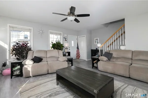 a kitchen with stainless steel appliances kitchen island granite countertop a refrigerator a stove a sink and white cabinets with wooden floor
