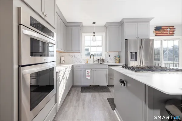 a kitchen that has a lot of white cabinets and stainless steel appliances