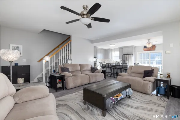 a living room with furniture a ceiling fan a lamp and a window