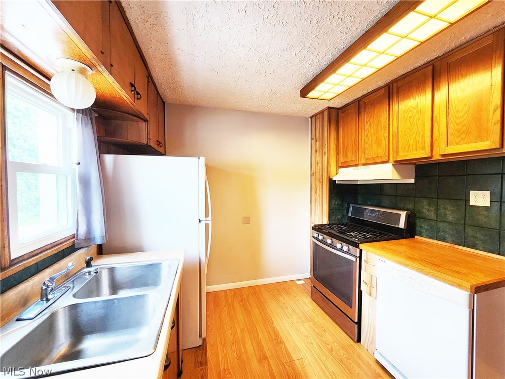 30 West Wilbeth Road, Unit A Akron, OH 44301 - Photo 7 of 16 Kitchen featuring light wood-type flooring, a textured ceiling, backsplash, gas range, and sink