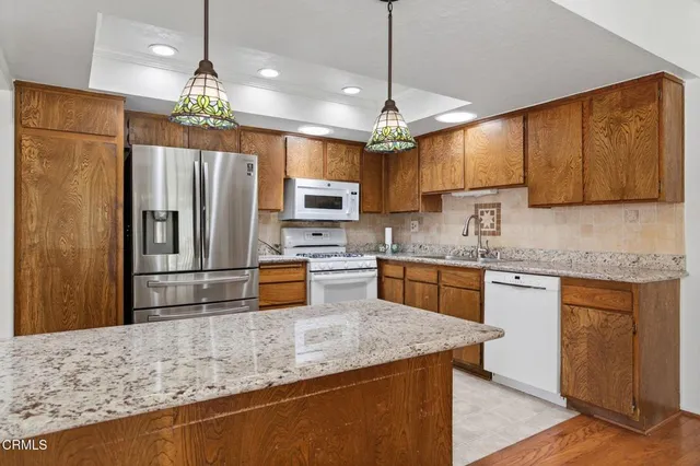 a kitchen with kitchen island granite countertop a refrigerator a sink and a stove