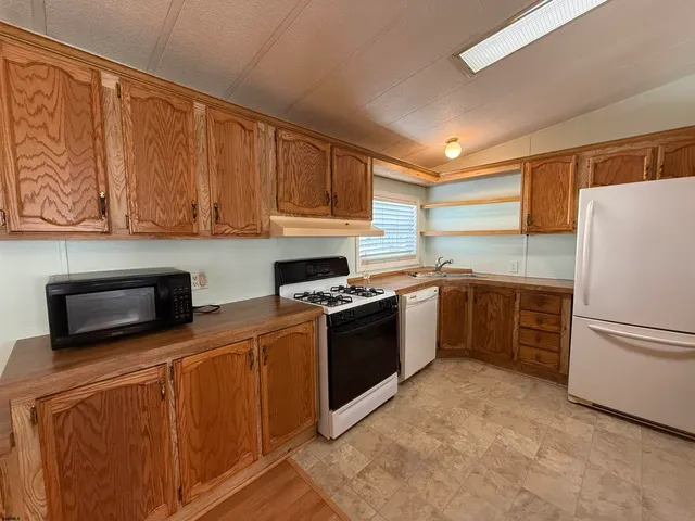 a kitchen with stainless steel appliances granite countertop a stove a sink and a refrigerator with white cabinets