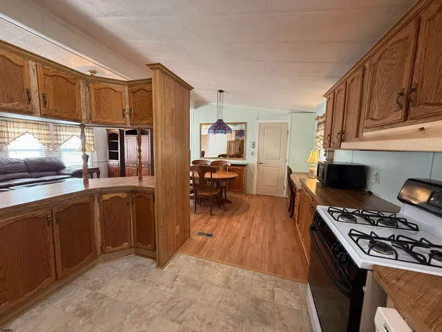 a kitchen with stainless steel appliances granite countertop a stove refrigerator and a view of living room