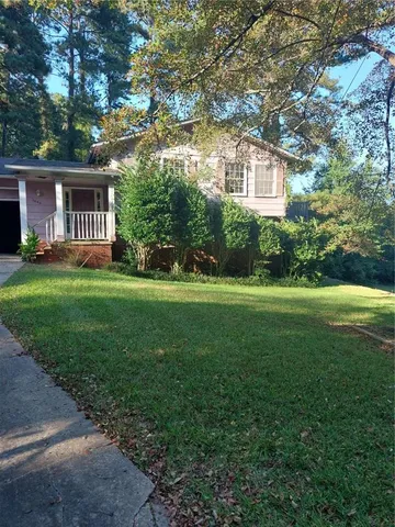 a view of a house next to a big yard and large trees