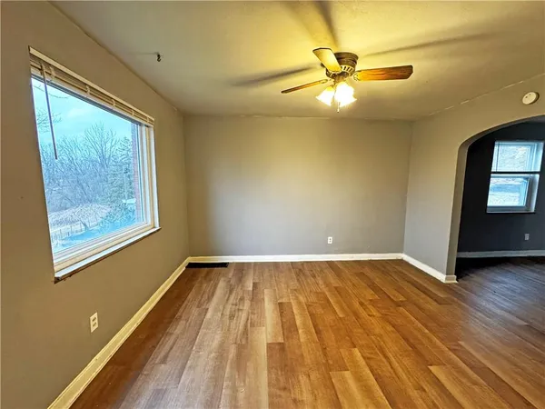 a view of an empty room with a window and wooden floor