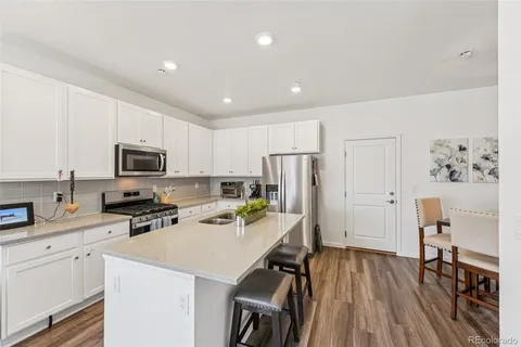 a kitchen with stainless steel appliances a refrigerator stove microwave and white cabinets