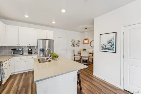 a kitchen with stainless steel appliances a refrigerator a sink a stove a dining table and chairs