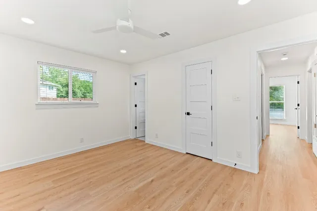 an empty room with wooden floor and windows
