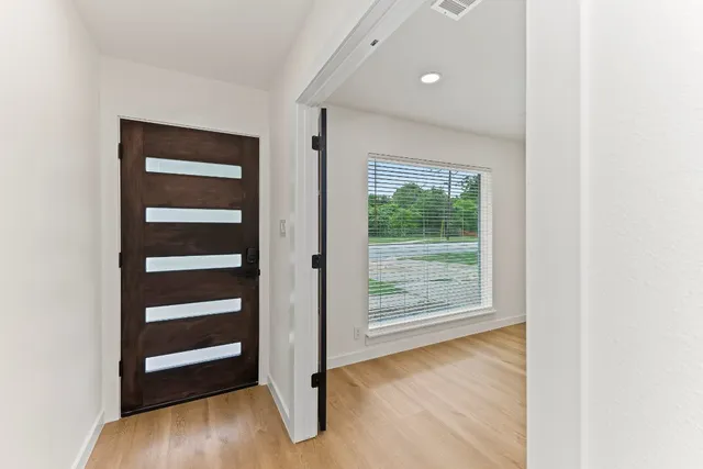 a view of an empty room with wooden floor and a window