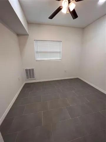 an empty room with a ceiling fan and a window