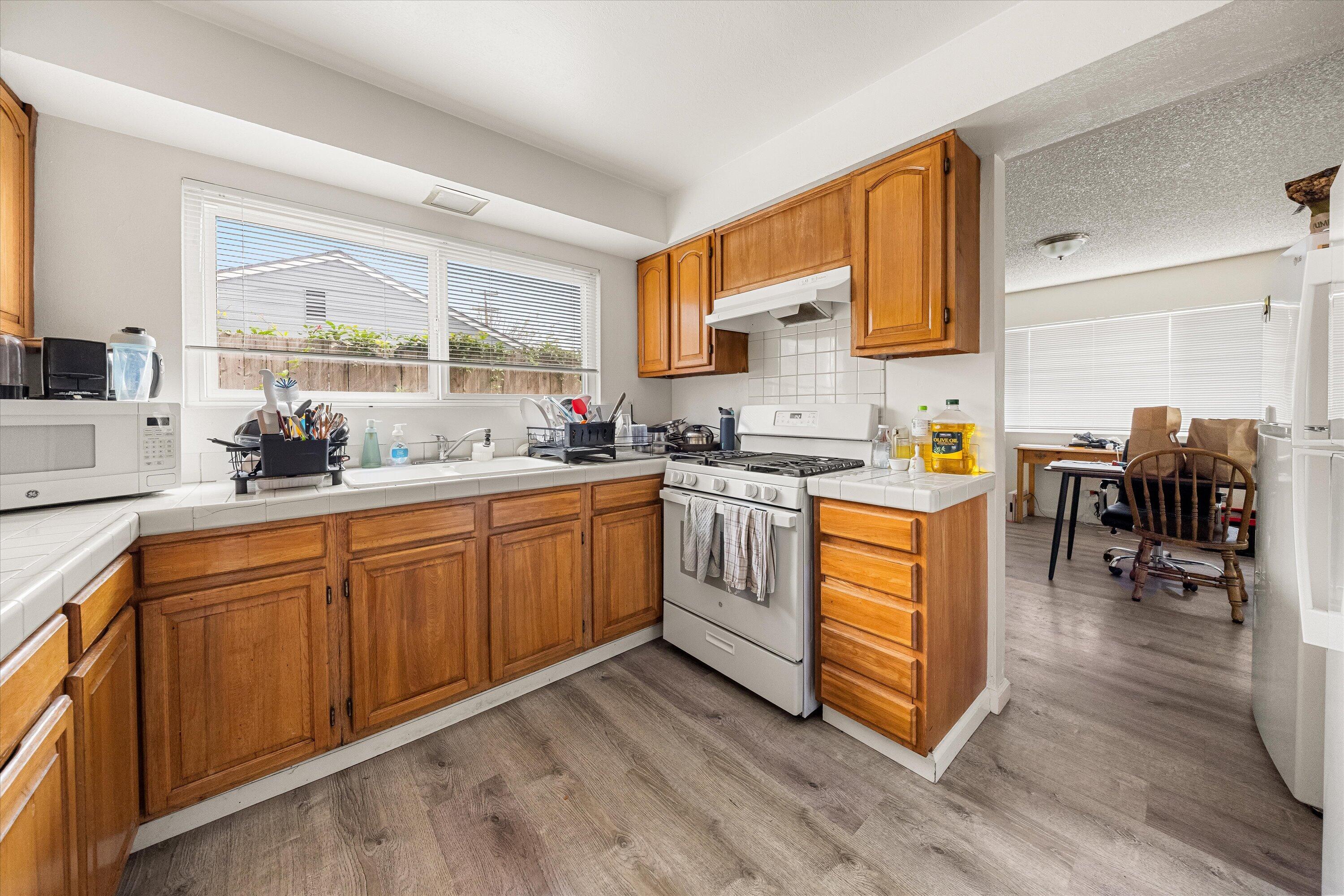 6724 Pasado Road Goleta, CA 93117 - Photo 9 of 24 a kitchen with wooden floors and white cabinets