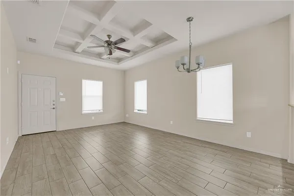 an empty room with wooden floor ceiling fan and windows
