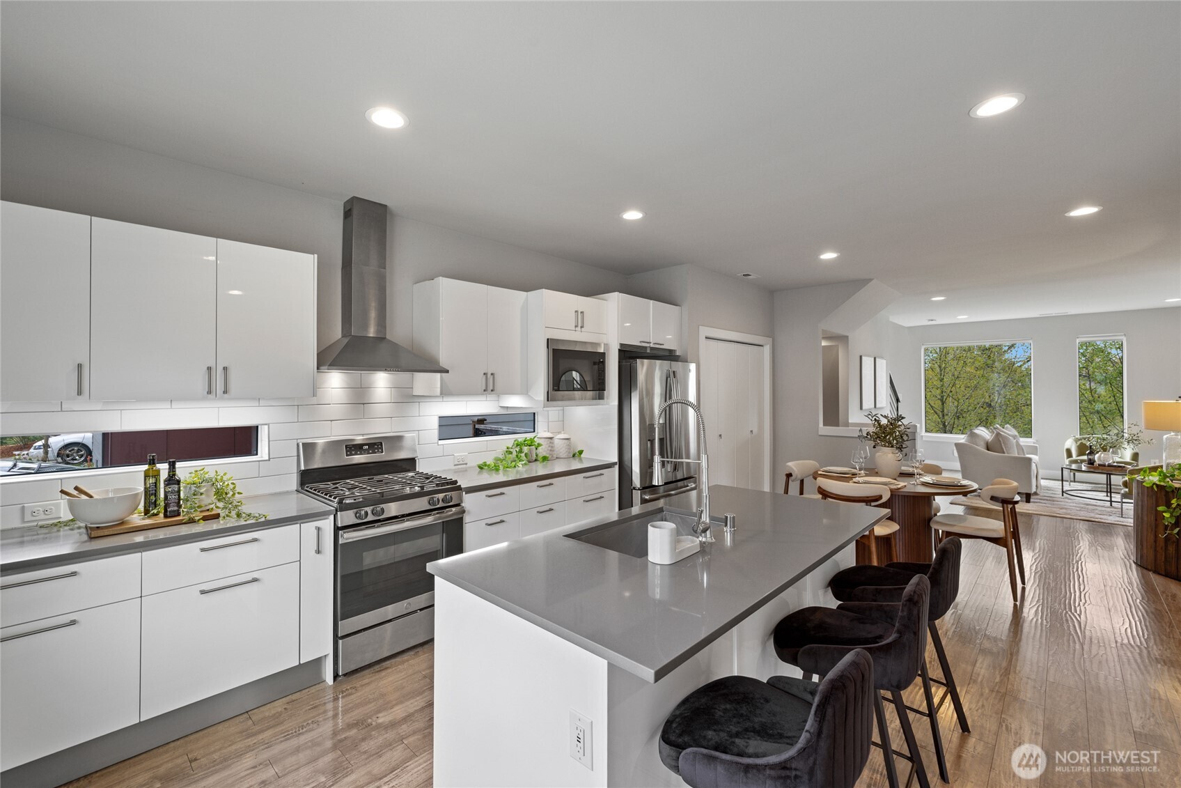 24903 123rd Place Southeast Kent, WA 98030 - Photo 5 of 40 a kitchen with stainless steel appliances a sink a stove a dining table and chairs with wooden floor
