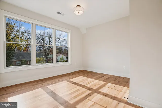 a view of an empty room with window and wooden floor