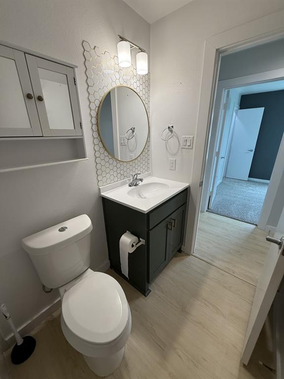 505 Thomas Street Terrell, TX 75160 - Photo 35 of 38 Bathroom featuring a vanity with a white countertop, circular mirror with a gold-tone frame, and a hexagonal tile backsplash