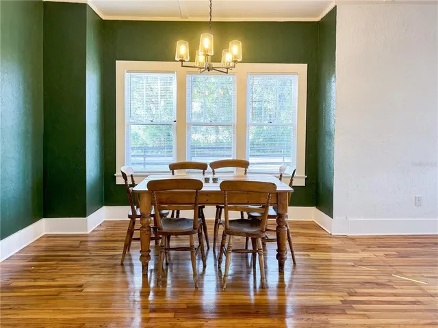 an empty room with wooden floor chandelier fan and windows
