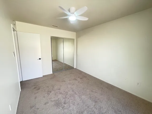 an empty room with a ceiling fan and a window