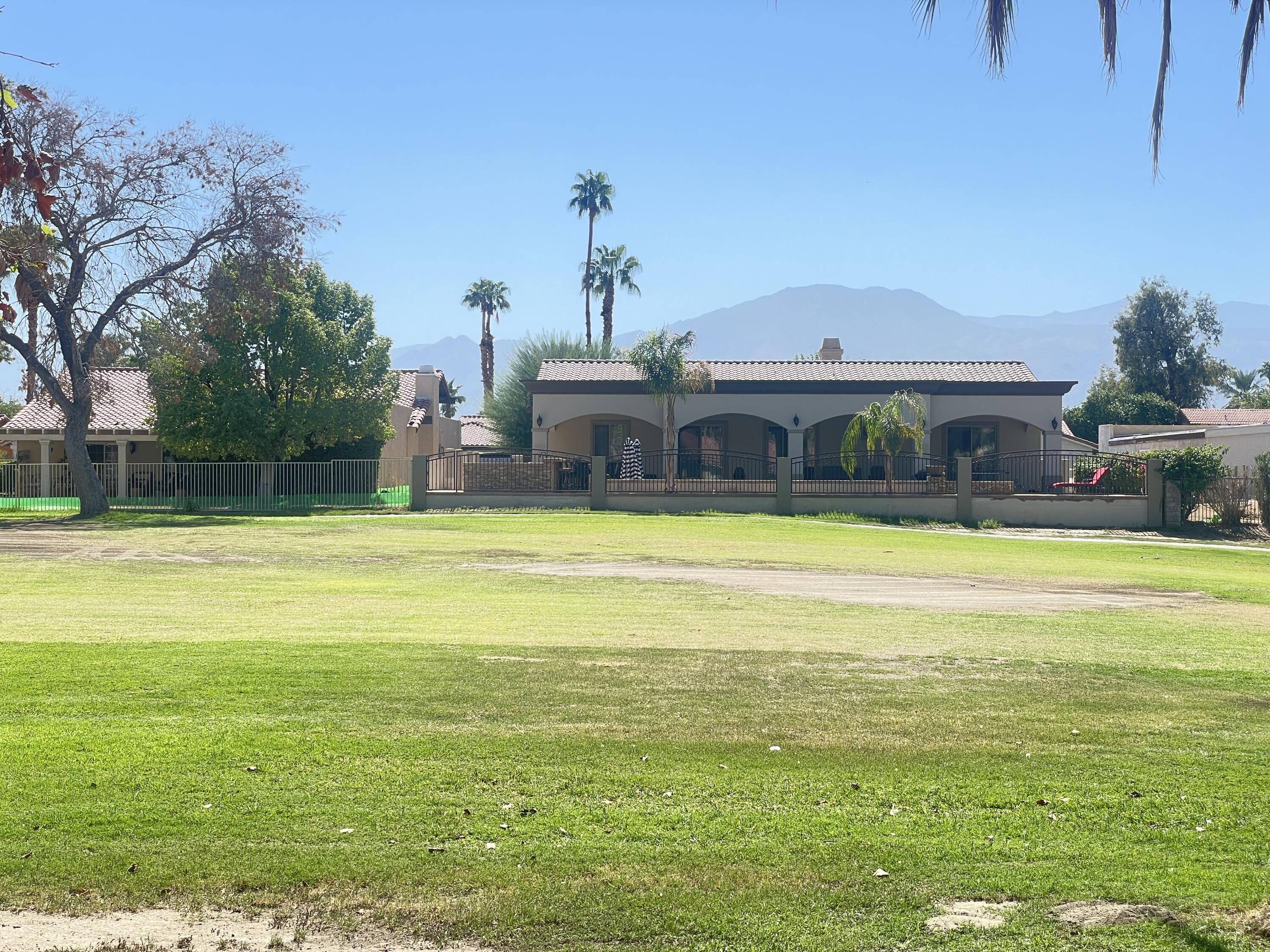 82567 Ave 48, Unit 36 Indio, CA 92201 - Photo 5 of 27 a view of a swimming pool with a lawn chairs under an umbrella