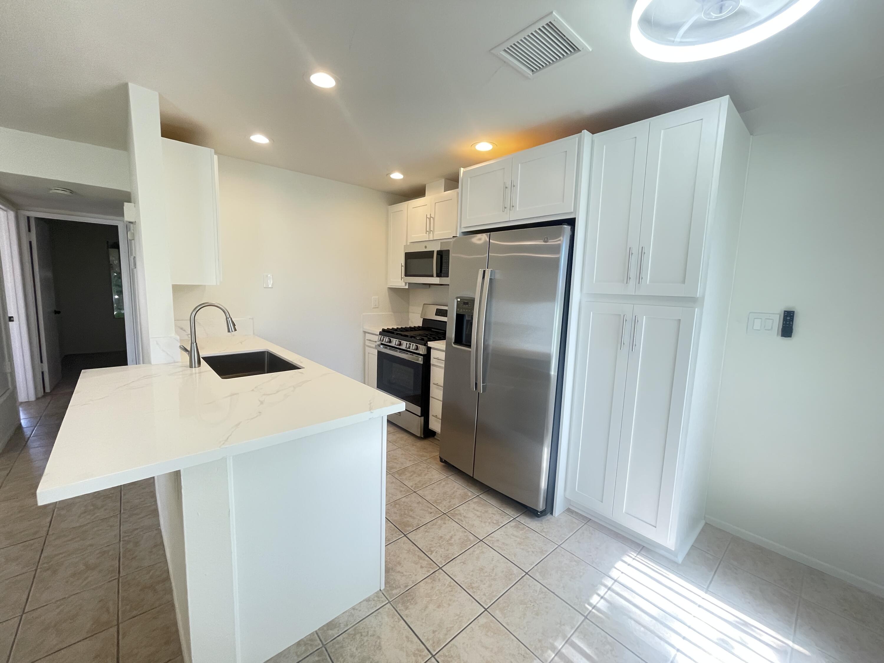 82567 Ave 48, Unit 36 Indio, CA 92201 - Photo 8 of 27 a kitchen with stainless steel appliances a refrigerator sink and microwave