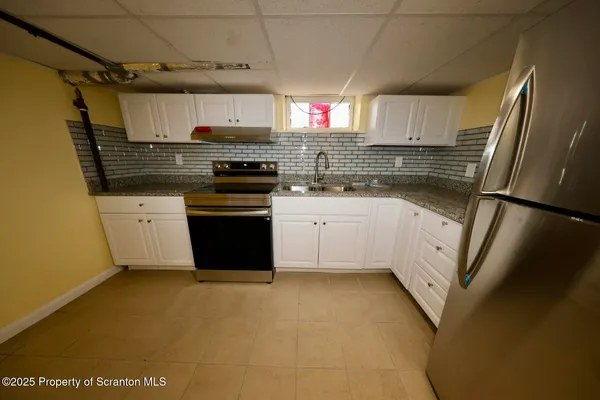 a kitchen with stainless steel appliances granite countertop a refrigerator a sink dishwasher a stove and white countertops with wooden floor