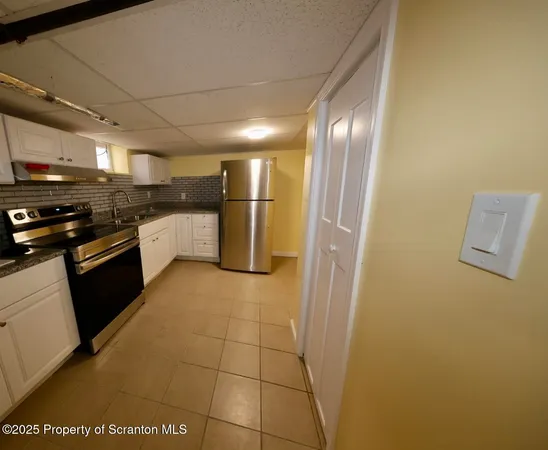 a kitchen with stainless steel appliances granite countertop a refrigerator a stove a sink and dishwasher with wooden floor