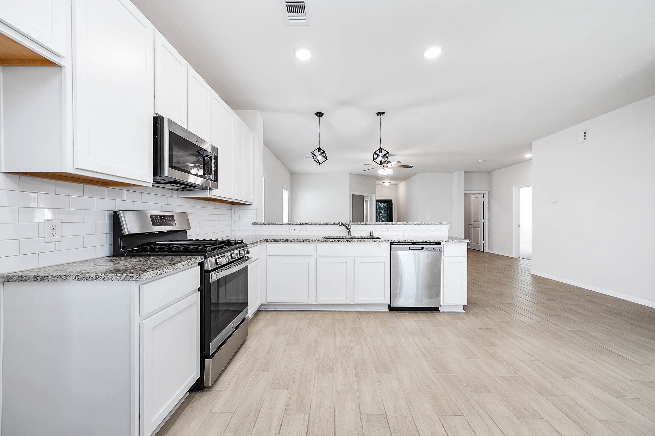 3611 Prairie Rose Trail Angleton, TX 77515 - Photo 11 of 25 a large kitchen with stainless steel appliances granite countertop a stove a sink and a microwave