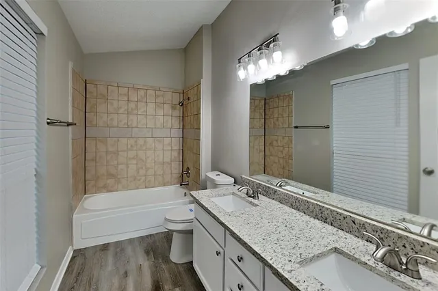 a bathroom with a granite countertop double vanity sink and a mirror