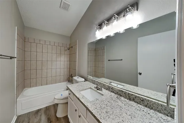 a view of a house with a small yard and large tree