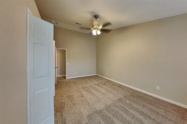 an empty room with a ceiling fan and a window