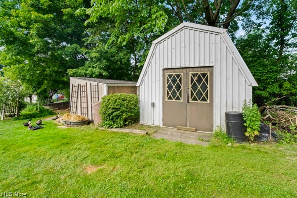 5030 Warren - Sharon Road Vienna, OH 44473 - Photo 9 of 50 White board-and-batten shed with gambrel roof and double doors featuring diamond-patterned window inserts