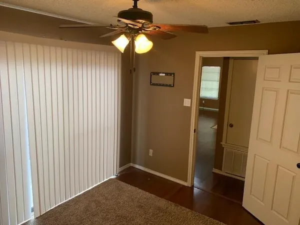 an empty room with wooden floor fan and windows
