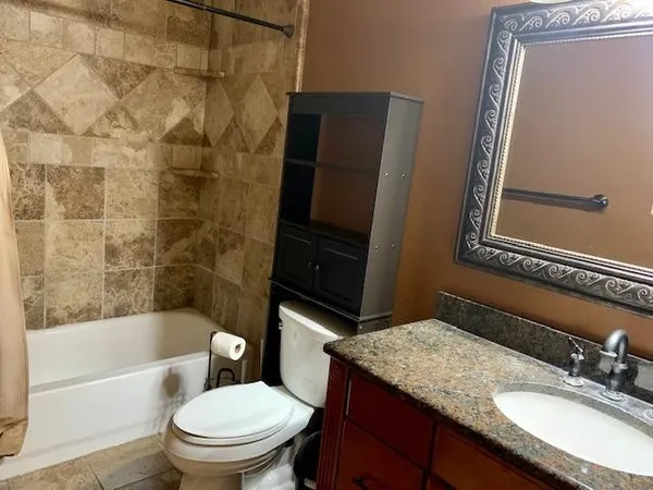 a bathroom with a granite countertop toilet sink and mirror