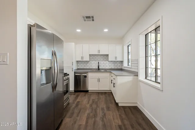 a kitchen with a white cabinets and wooden floor