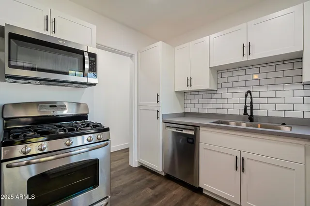 a kitchen with cabinets stainless steel appliances a sink and a stove