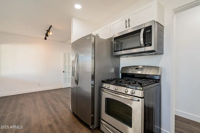 a kitchen with stainless steel appliances a stove a microwave and a hard wood floor