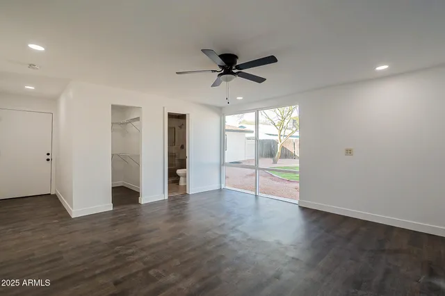 an empty room with wooden floor fan and windows