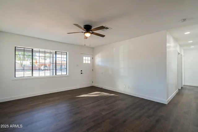 a view of empty room with wooden floor and fan