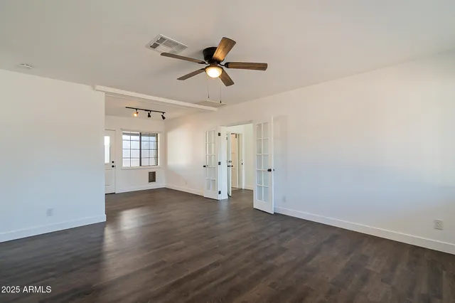 a view of empty room with wooden floor and ceiling fan