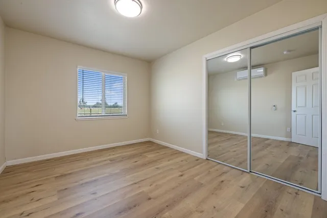 a view of an empty room with wooden floor and a closet