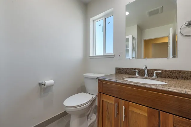 a bathroom with a granite countertop toilet sink and mirror